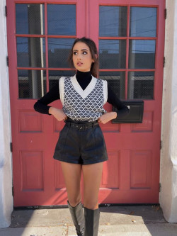 Rocking a black and white houndstooth sweater vest over a turtleneck, paired with shorts for a retro-inspired look: 