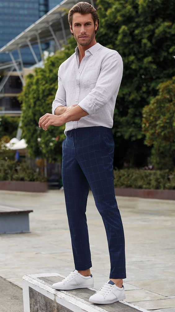 Premium Photo  Man in a white shirt and blue trousers is tying his shoes  sitting on a chair closeup