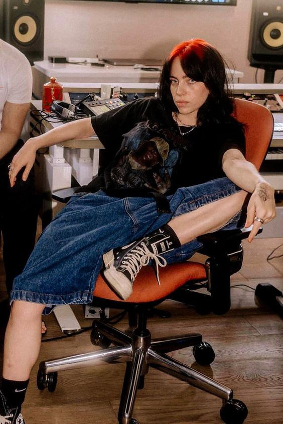 Have you seen her in that denim outfit? It's just gorgeous, perfect for chilling in the studio: sitting,  anderson hopkins,  Billie Eilish,  beauty salon,  Black hair  